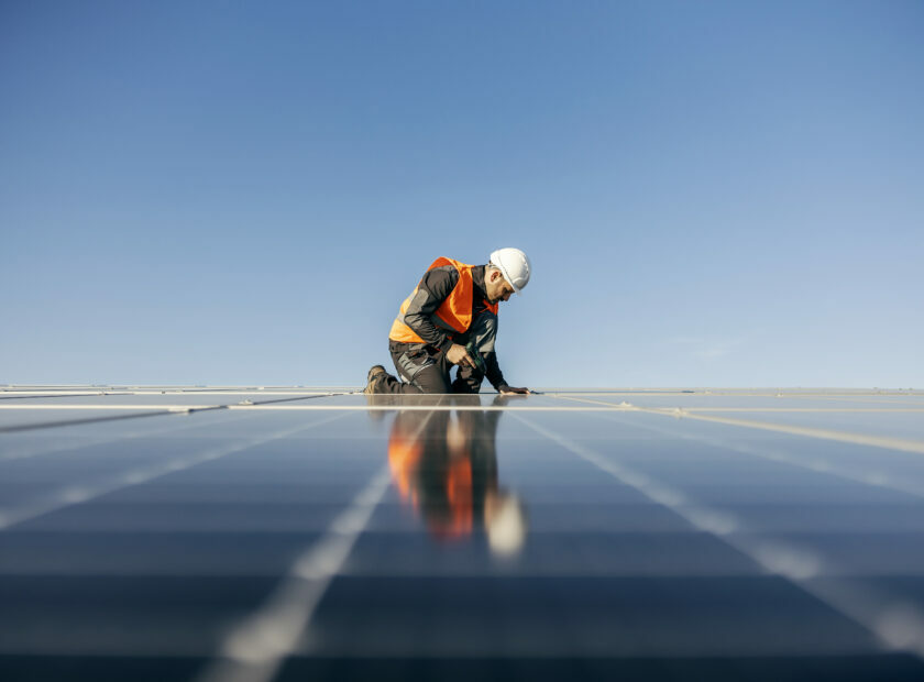 Worker kneeling and sets solar panel.